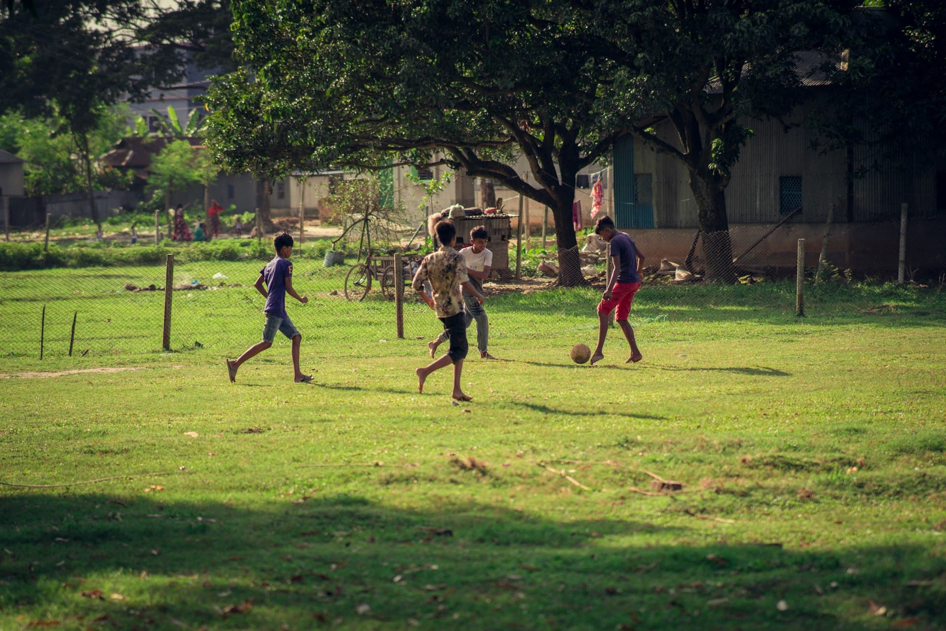 Kids playing football on a grass pitch